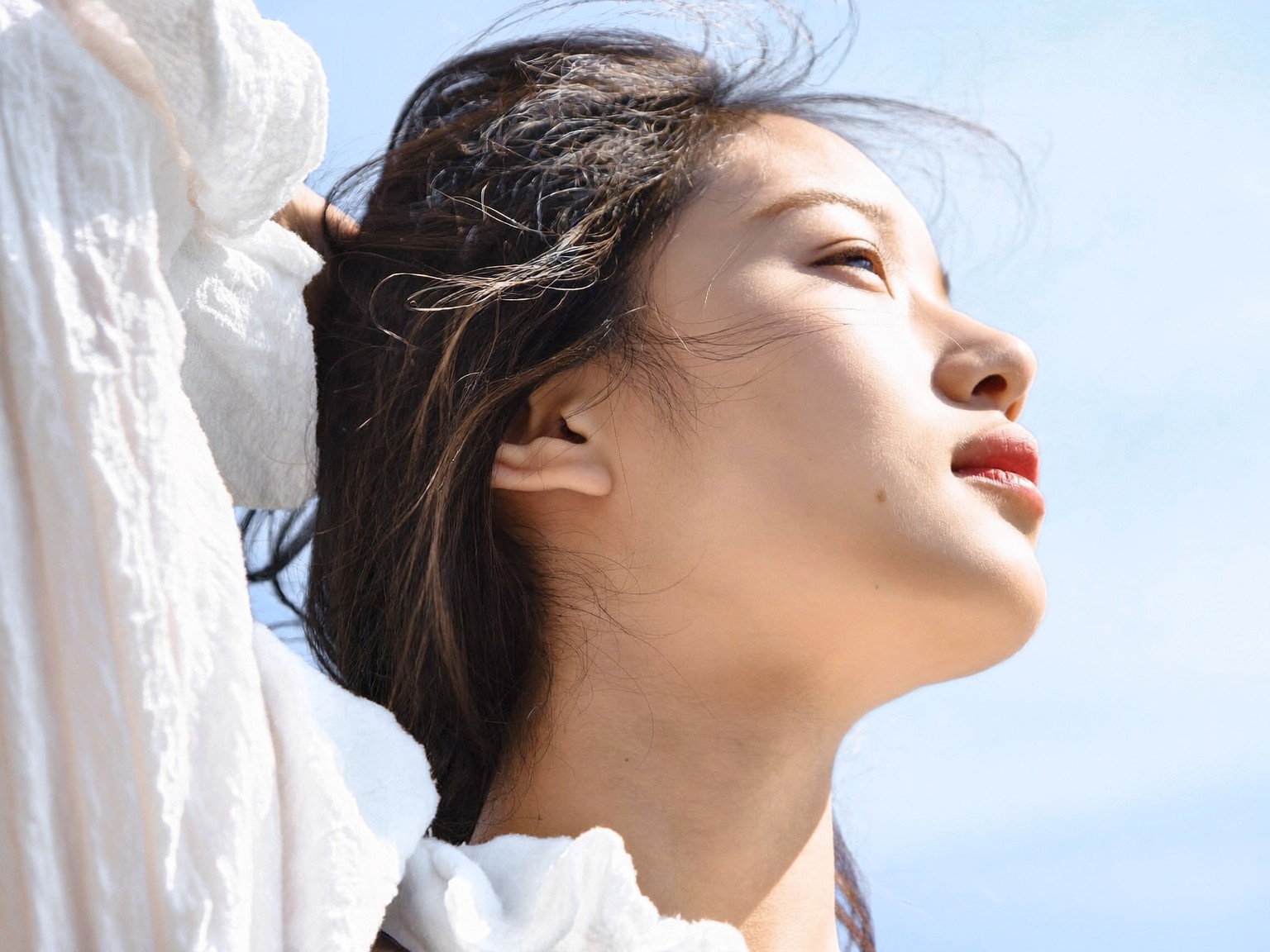 햇살 아래 하늘을 바라보는 여성의 옆모습